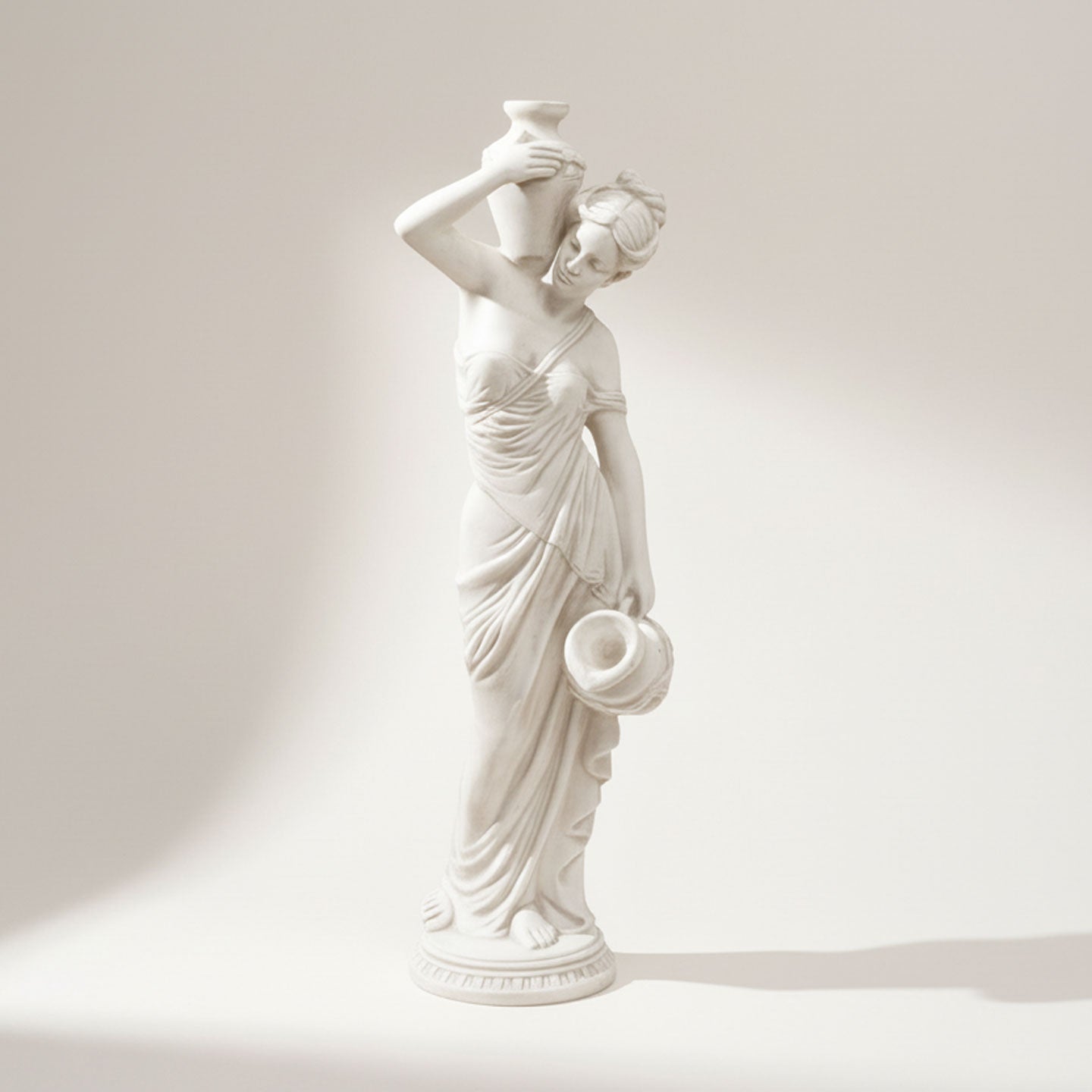 White classical statue of the goddess Maia holding a vase on a light beige background