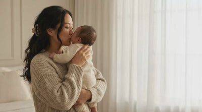 An Asian woman gently rocks, kisses and nuzzles her newborn baby